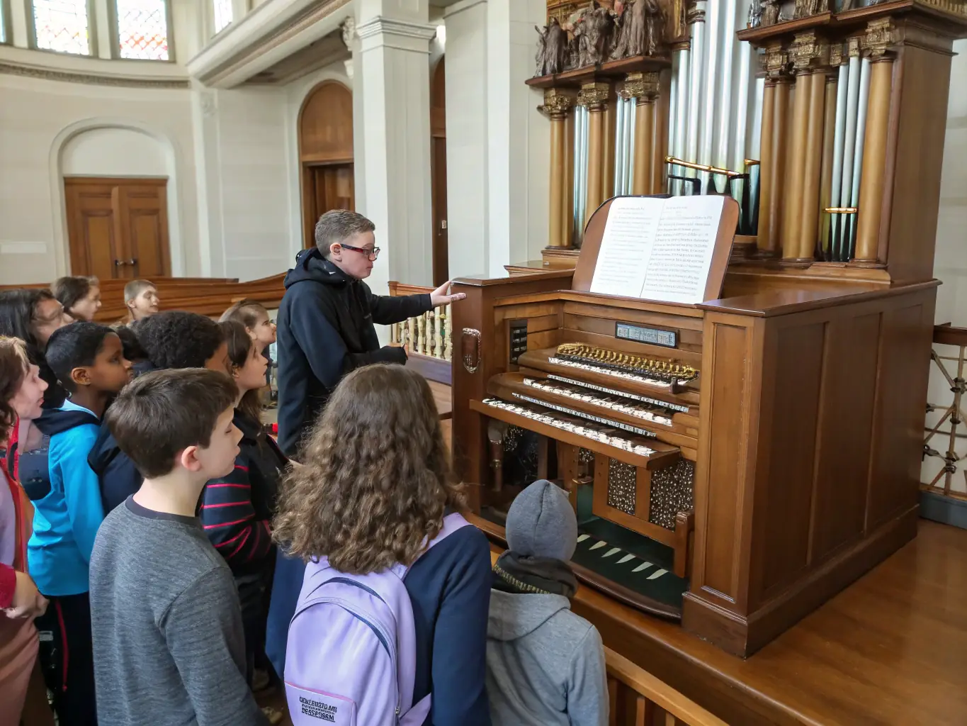 A classroom setting where an instructor is teaching a group of students about the history and mechanics of church organs.